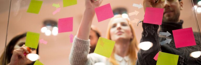 Een groep mensen met plakbriefjes die brainstormen over inhoudsideeën voor hun website terwijl ze inspiratie opdoen in de spiegel.