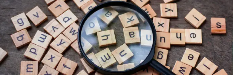 A magnifying glass placed over scattered wooden letter tiles on a wooden surface, highlighting several tiles beneath the lens—symbolizing the focused clarity essential in the conversational era of search marketing.